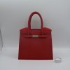Print Luxe Handbag Vase Een levendige rode luxe handtas vaas, 3D-geprint, met een subtiel bladpatroon en een zilveren sluiting.