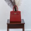 Print Luxe Handbag Vase Een levendige rode luxe handtas vaas, 3D-geprint, met een subtiel bladpatroon en een zilveren sluiting.