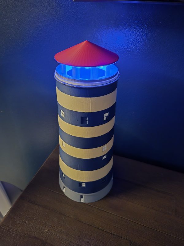 De Watertoren van Bredene – 3D-geprint met RGB-verlichting Breng een stukje Bredene in huis met deze gedetailleerde 3D-geprinte replica van de iconische Watertoren! Dit unieke decoratiestuk heeft een realistisch ontwerp met blauwe en gele banden en kleine vierkante ramen. De rode top van de toren geeft een herkenbare uitstraling, terwijl de ingebouwde RGB-verlichting een sfeervol en dynamisch effect creëert. Perfect als opvallend interieuraccessoire, geschenk of verzamelobject voor liefhebbers van architectuur en lokale landmarks.