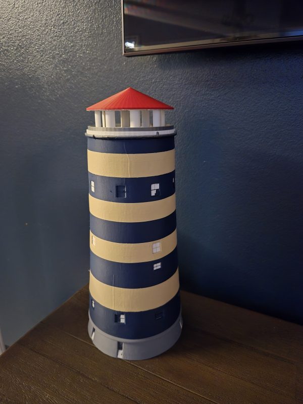 De Watertoren van Bredene – 3D-geprint met RGB-verlichting Breng een stukje Bredene in huis met deze gedetailleerde 3D-geprinte replica van de iconische Watertoren! Dit unieke decoratiestuk heeft een realistisch ontwerp met blauwe en gele banden en kleine vierkante ramen. De rode top van de toren geeft een herkenbare uitstraling, terwijl de ingebouwde RGB-verlichting een sfeervol en dynamisch effect creëert. Perfect als opvallend interieuraccessoire, geschenk of verzamelobject voor liefhebbers van architectuur en lokale landmarks.