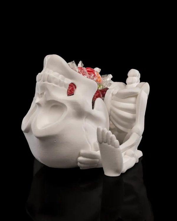 Een gedetailleerde 3D-geprinte CRANI-YUM CANDY HOLDER in de vorm van een skelet dat een schedel vasthoudt. De schedel dient als snoephouder. Het witte skelet heeft zichtbare ribben en botstructuren, terwijl de uitgesneden oogkassen en mond van de schedel een griezelig, speels effect geven.