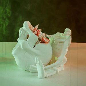 Een gedetailleerde 3D-geprinte CRANI-YUM CANDY HOLDER in de vorm van een skelet dat een schedel vasthoudt. De schedel dient als snoephouder. Het witte skelet heeft zichtbare ribben en botstructuren, terwijl de uitgesneden oogkassen en mond van de schedel een griezelig, speels effect geven.