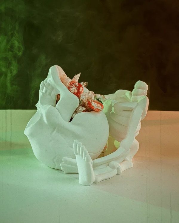 Een gedetailleerde 3D-geprinte CRANI-YUM CANDY HOLDER in de vorm van een skelet dat een schedel vasthoudt. De schedel dient als snoephouder. Het witte skelet heeft zichtbare ribben en botstructuren, terwijl de uitgesneden oogkassen en mond van de schedel een griezelig, speels effect geven.